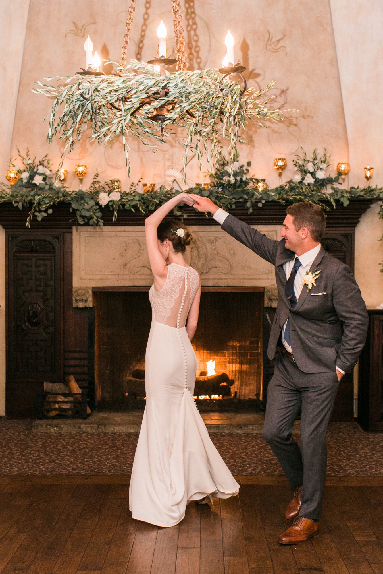 Bride twirling beside a full floral arrangement by the fireplace
