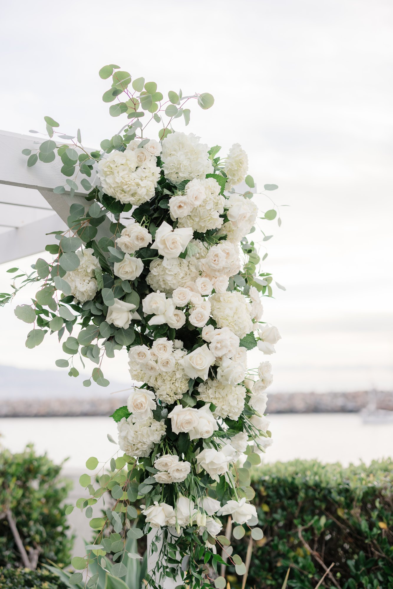 White floral arch at a coastal ceremony